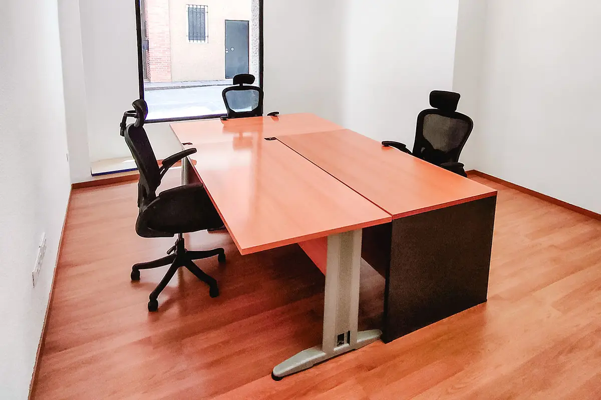 Oficina privada equipada con mesas, sillas de oficina y estantería, en Muon Cowork Granada. | Servicios Oficina Privada Centro Granada